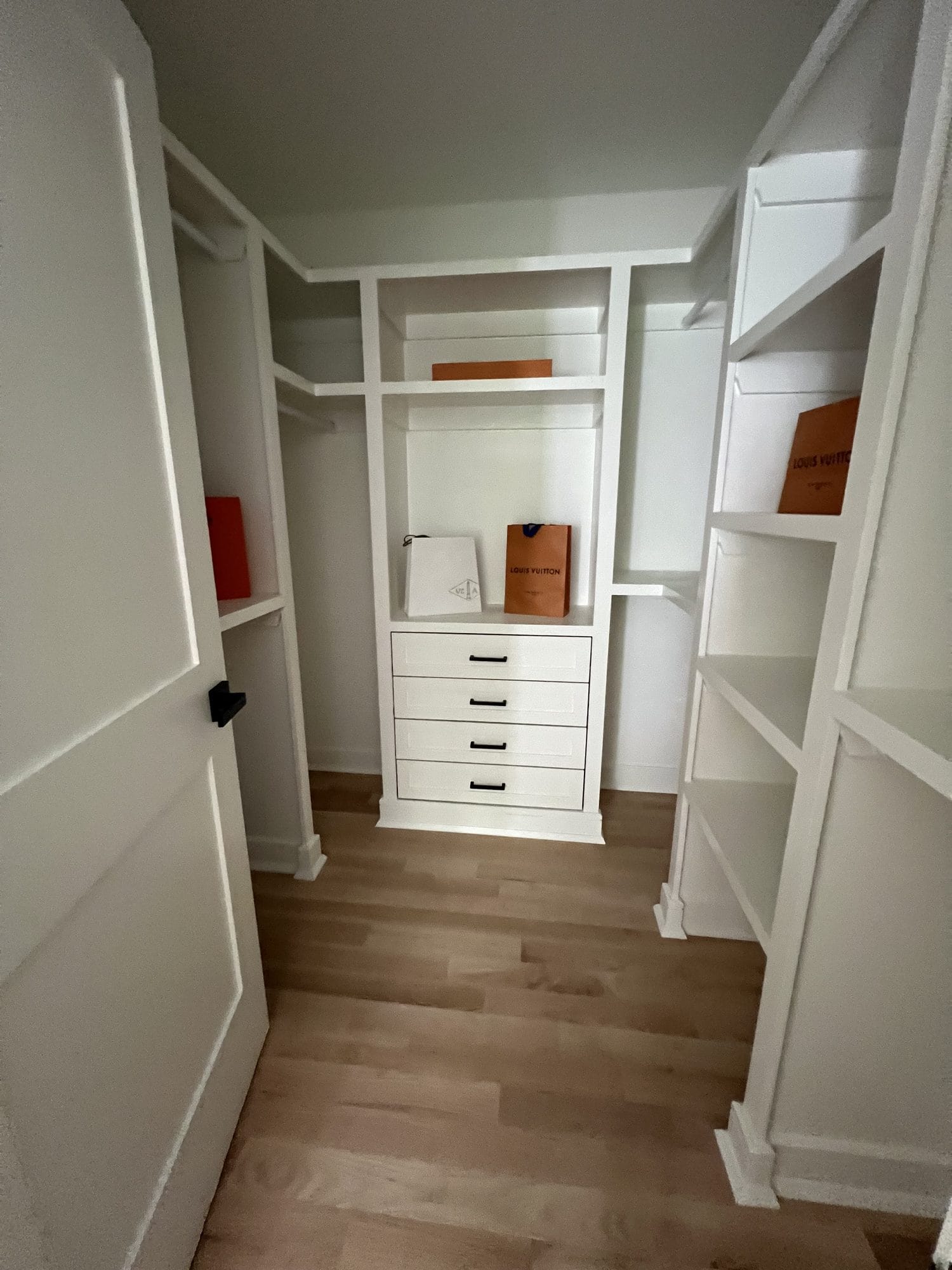 Custom walk-in closet with white built-in wardrobes, drawers, and open shelving